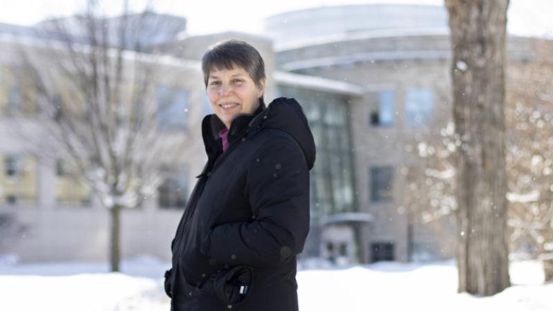 Nancy Wall, wearing a black winter coat, stands in front of Steitz Hall.