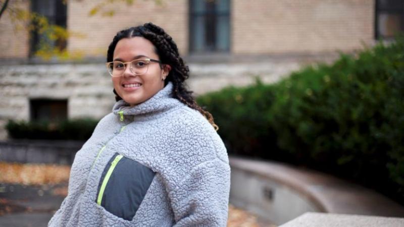Meralis Alvarez, wearing a grey coat, smiles at the camera.