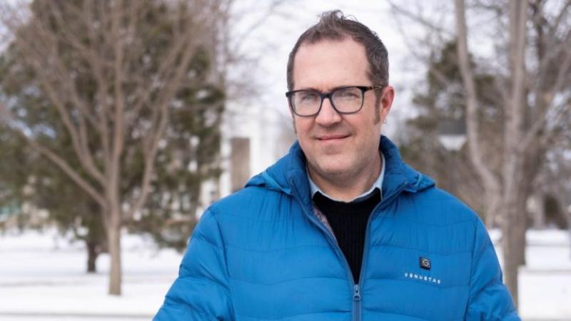 Benjamin Rinehart, wearing a blue coat, smiles at the camera.