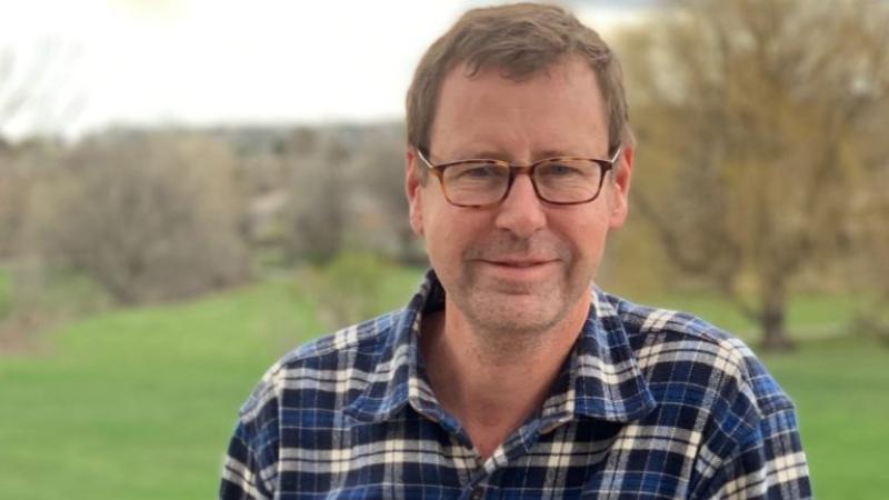 Tom Zoellner, wearing a blue plaid shirt, smiles at the camera.