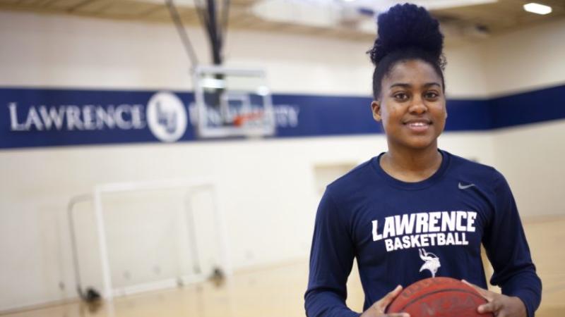 Shonell Benjamin, wearing a Lawrence basketball shirt, stands holding a basketball.