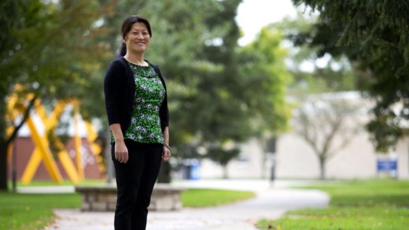 Dominica Chang, wearing a green shirt, stands on Main Hall Green.