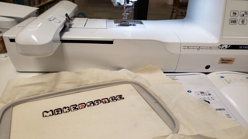 Word makerspace embroidered into fabric next to the embroidery machine.