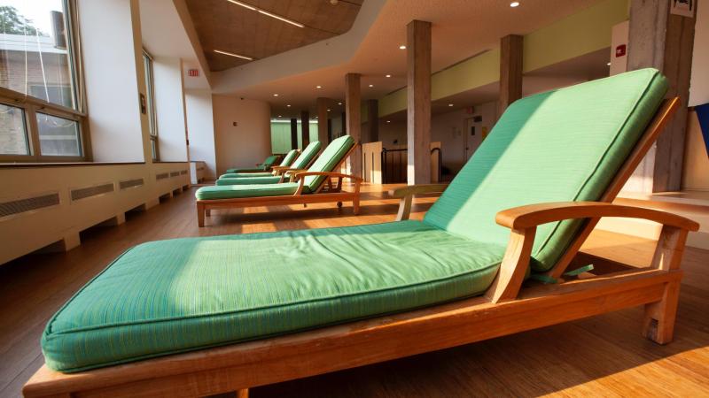 row of five soft green chaise lounge chairs in dorm common room