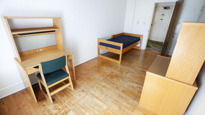 white room with wooden desk and dresser and XL twin bed 