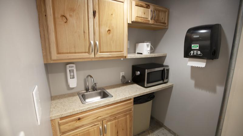 kitchenette with wood cabinets, a sink, microwave, toaster, and paper towel dispenser 