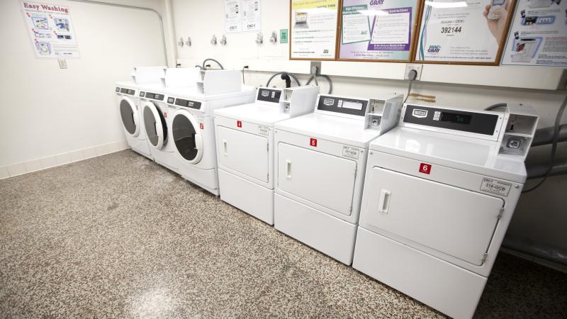 room with three washers and dryers along a wall with posters