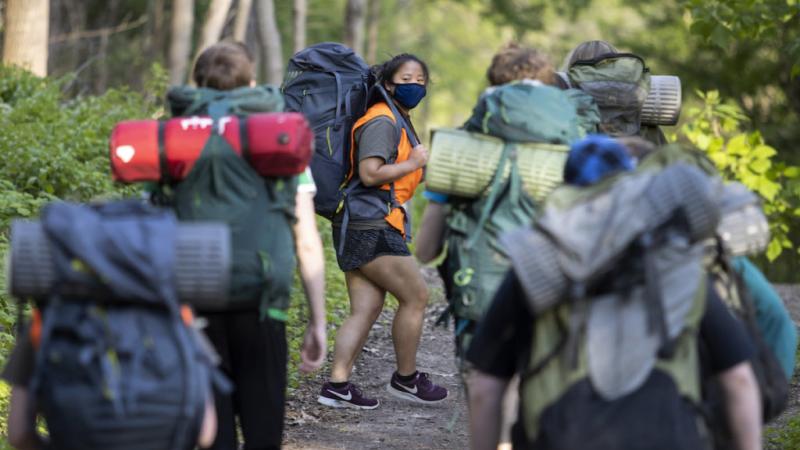 Students hiking with backpacks and camping gear 