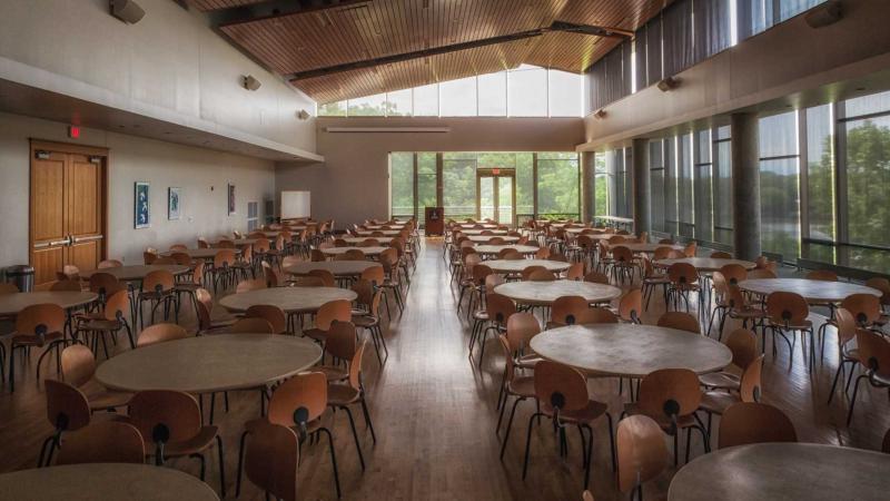 Large empty room filled with neat rows of round tables surrounded by chairs