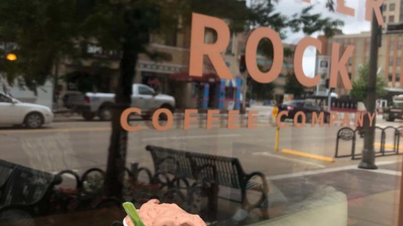 Hand holding an ice-cream cup in front of a Copper Rock Coffee sign 