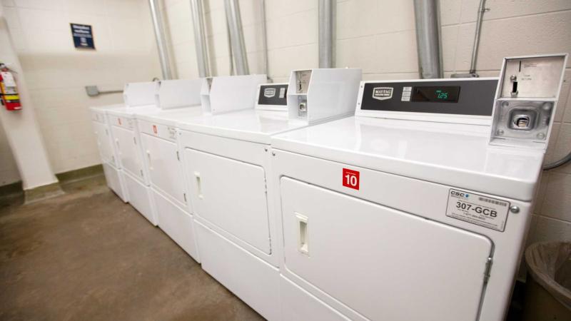 Large room with several washing machines and dryers along its walls