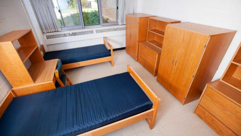 Large room with window the width of the wall, 2 XL beds, 2 desks and shelves and drawers, and a large cabinet