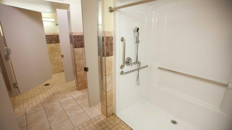 Shared bathroom with long shower stall and several smaller shower stalls next to it