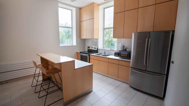 Kitchen with island counter with bar and 3 stools, a full-range stove, sink, toaster oven, fridge and cabinets