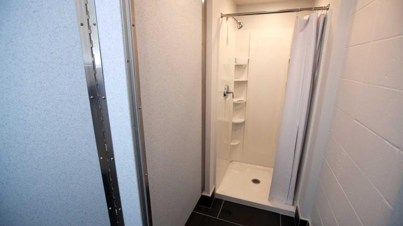 White shower with white curtain and light overhead