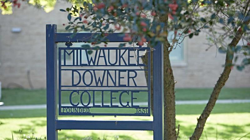 Blue iron post under tree with words Milwaukee Downer College Founded 1851