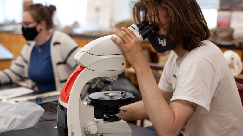 geoscience student looking into microscope 