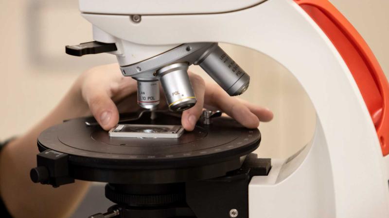 Hand adjusting lunar rock sample under the microscope in a geoscience class