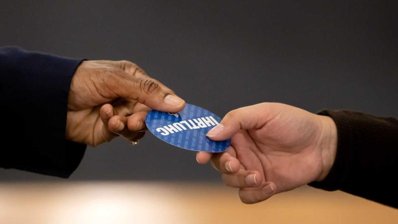 Close-up of Laurie Carter, Lawrence University’s President, hands out a sticker while greeting students at the President’s Handshake in Memorial Chapel