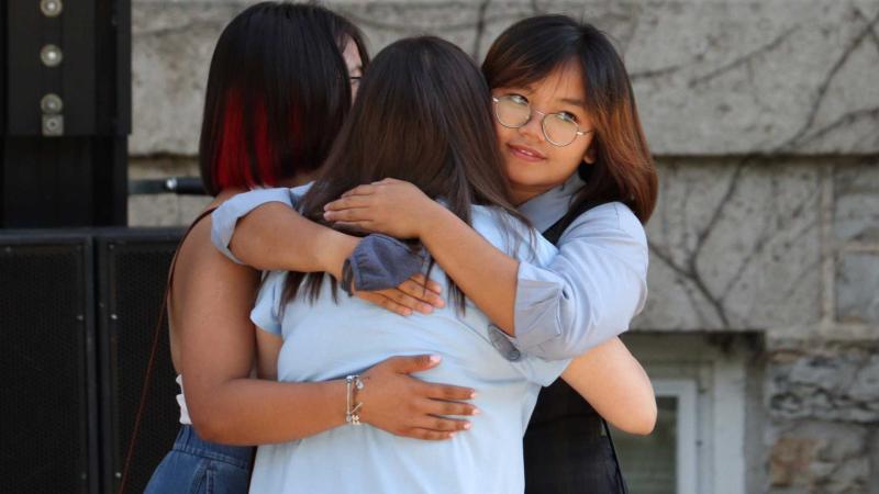 Three students hugging each other during the President's Welcome.