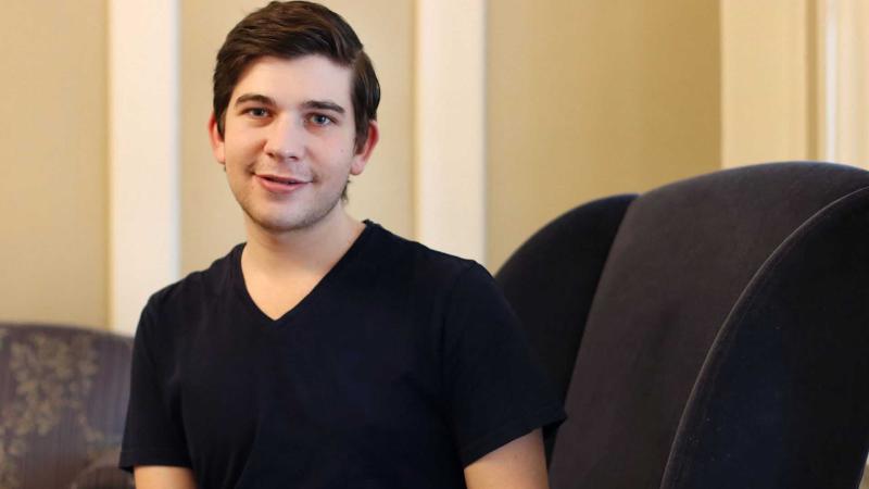 Jason Bernheimer sits in a black chair with his hands resting on the armrest.