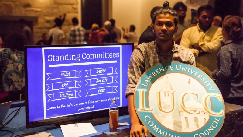 Member of Lawrence University Common Council next to standing committee powerpoint holding organization logo