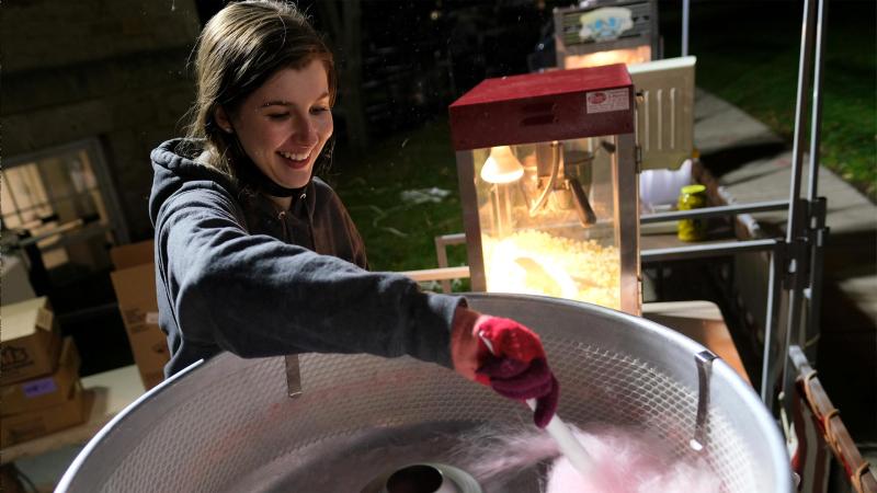 Student prepares cotton candy for students at the Blue and White Weekend Carnival 