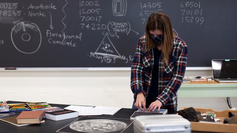 Student working in lab with chalkboard in background