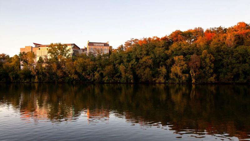 The Warch Campus Center and Sage Hall stick out among the changing fall colors along the Fox River at sunset