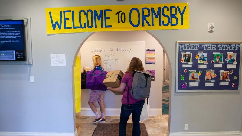 Students are moving boxes into Ormsby Hall on move-in day.