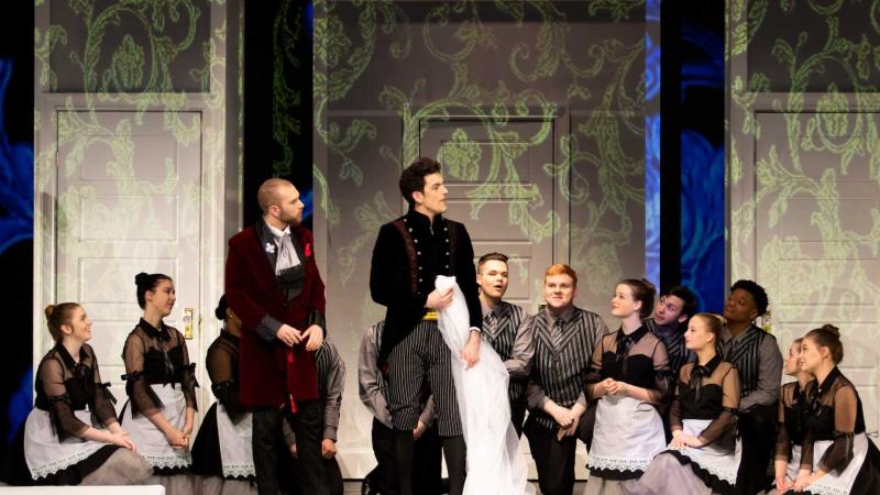 Erik Nordstrom as Count Almaviva and Max Muter as Figaro stand while chorus kneels down watching them, during a dress rehearsal for The Marriage of Figaro.