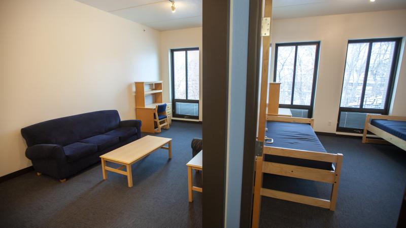 Double room setup in Hiett Hall, with common living space seen through open door to the left and bedroom seen through door on the right.