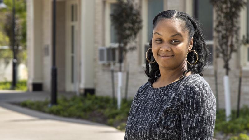 Brittany Bell, wearing a black and silver shirt, stands in front of Memorial Hall.