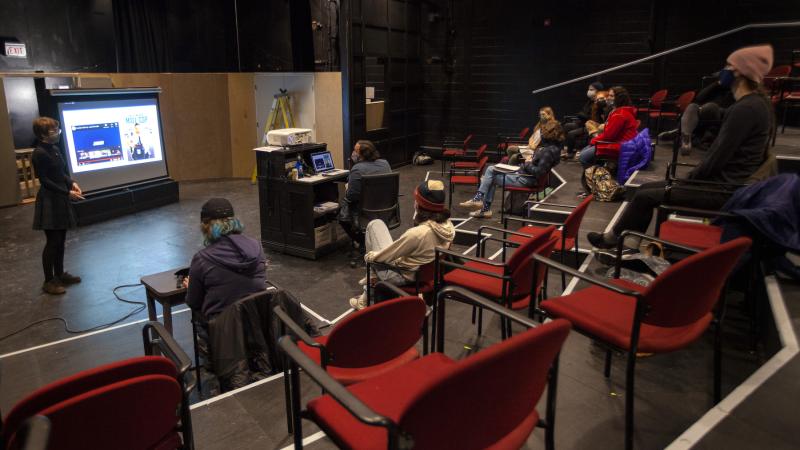 Students giving final presentations during a December Term class taking place in a theatre.