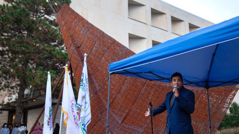 Architect Chris Cornelius speaks under a tent next to the crane sculpture he designed during Lawrence's sixth annual Indigenous Peoples' Day Celebration.