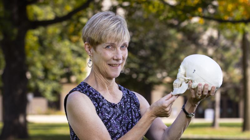 Kathy Privatt holds out a fake human skull on Main Hall Green.