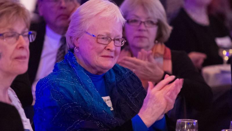 Margaret Carroll clapping while at a dinner banquet.