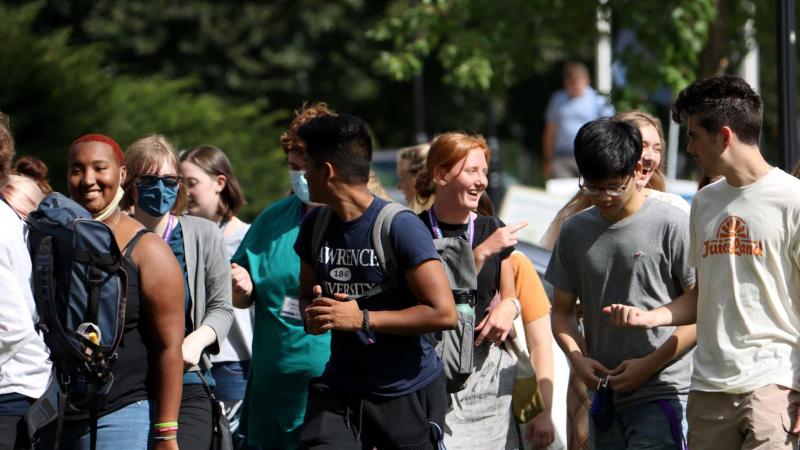 Large group of new students walking and chatting with one another.