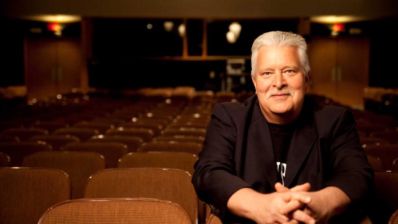 Fred Sturm sitting in an audience seat in an empty auditorium 