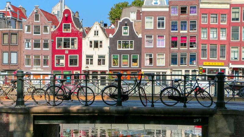 Bikes on bridge with colorful row houses in background in Amsterdam, Netherlands
