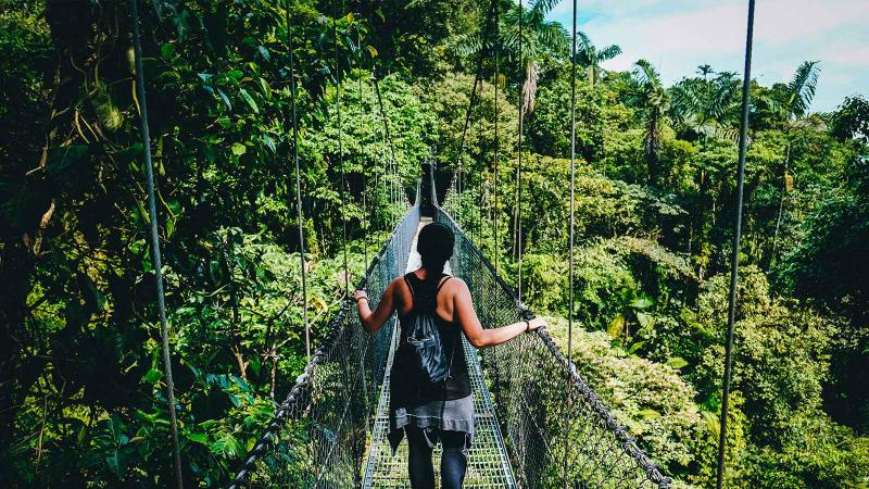 Woman walking on a bridge in Costa Rica surrounded by greenery