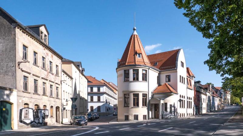 Three-story house with red tiled roof on street corner in Freiburg Germany