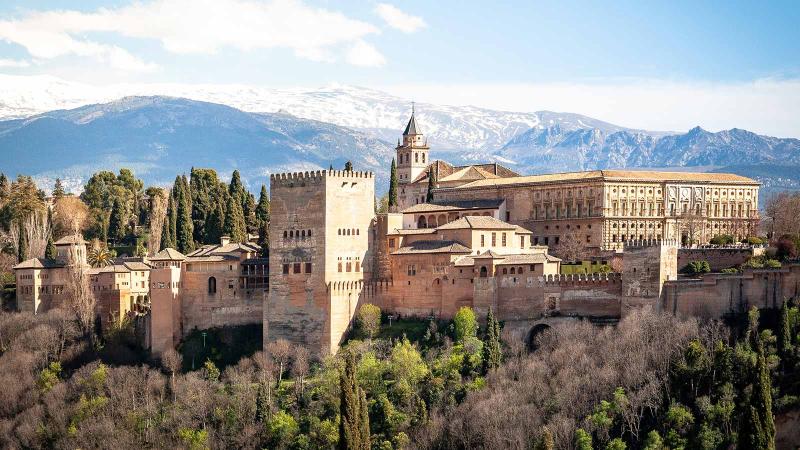 Aerial of Alhambra from a distance with Sierra Nevada mountains in the background in Granada, Spain