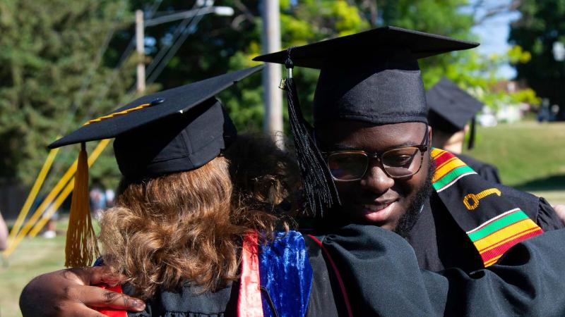 Grads hug during Commencement 2021