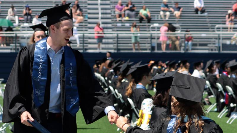Students fist-bump at Commencement
