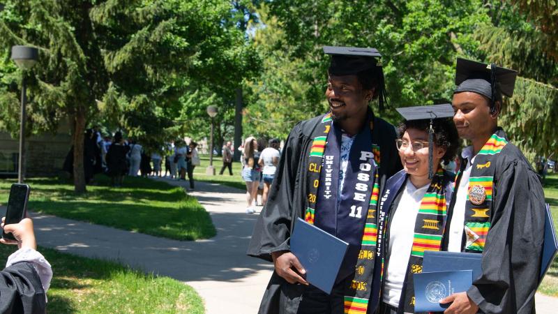 Recent graduates pose in their regalia for a photo during on Main Hall Green