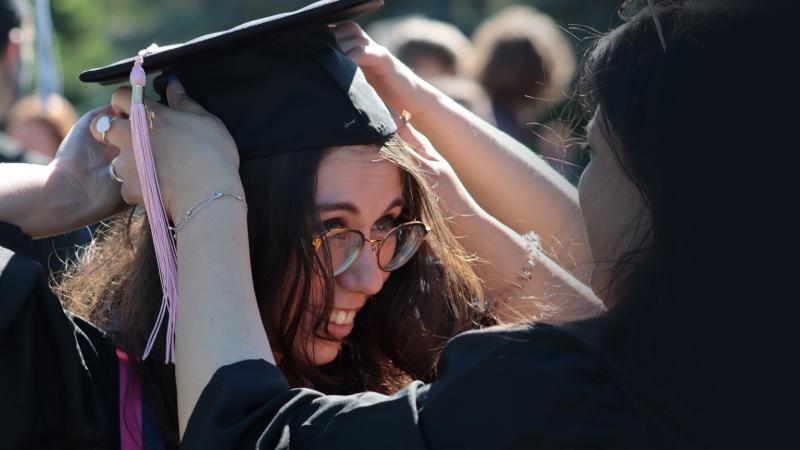 Student adjusts mortar board at Commencement 2021