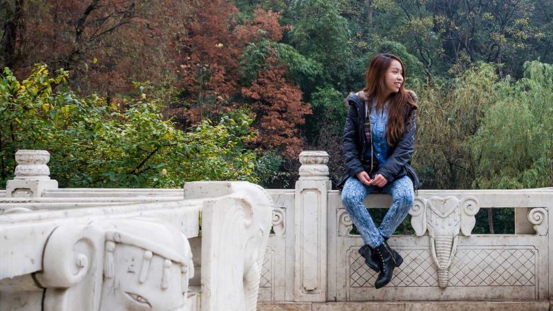 Student sitting on stone wall in Guiyang & Guizhou Province
