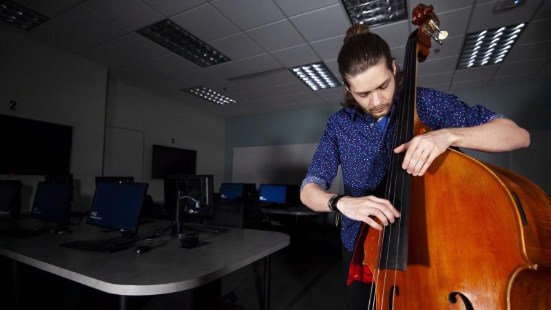 Andrew Foley plays the bass inside an empty computer lab.
