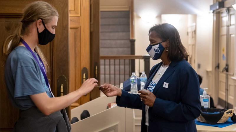 Laurie Carter, Lawrence University’s President, hands out a sticker while greeting students at the President’s Handshake in Memorial Chapel.
